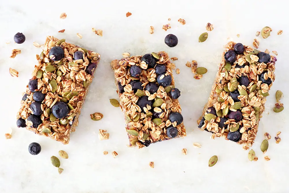 Superfoodbreakfastbarsaboveviewonmarblebackgroundblueberriesseedsnuts